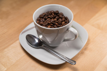 Cup filled with coffee beans on a saucer