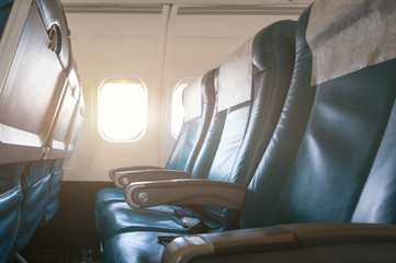 Interior of airplane with empty seats and sunlight at the window. Travel concept