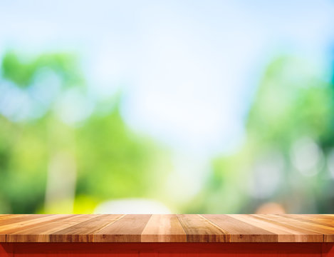 Empty brown wood table top with sun and blur green tree bokeh ba