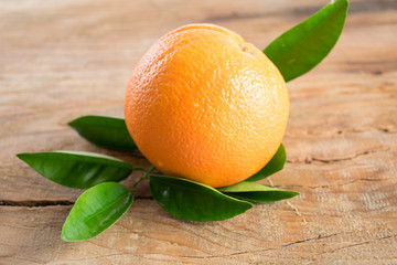 Orange fruit with leaves on wooden background