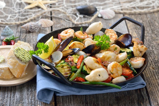 Gebratene gemischte Meeresfr&uuml;chte mit frischem buntem Gem&uuml;se, dazu Baguette mit Kr&auml;uterbutter -  Fried mixed seafood and fresh vegetables, served with baguette with herb butter