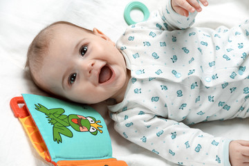 Cute smiling infant lying in his bed with different toys