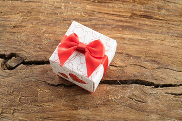 Gift box with two red hearts on side on wooden background