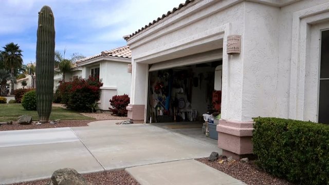 A side angle view of a home garage door closing automatically in a typical Phoenix neighborhood.  	