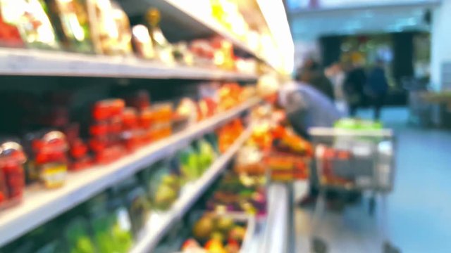 Supermarket interior with buyers, vegetable department, blurred defocused background
