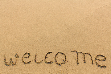 Welcome - hand-written on sandy beach.