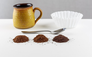 Coffee Blends:
A macro picture of three primary shades or blends of coffee which are standard house blend, blonde and dark roast.  The picture features a coffee cup, filter and a spoon as a backdrop.