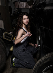 Plakat sexy girl mechanic sitting on a tire holding a wrench in his hand. colorless life concept