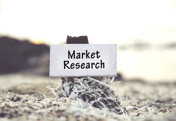 concept image, word MARKET RESEARCH on white canvas frame with blurred beach and clam shell background.