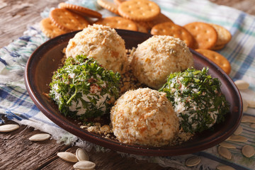 Goat Cheese balls with crackers, herbs and pumpkin seeds close-up. horizontal
