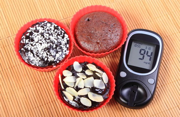 Glucometer and chocolate muffins in red cups