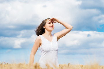 Fototapeta premium Young and happy woman in a meadow of rye