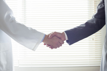 握手する医師とビジネスマンの手