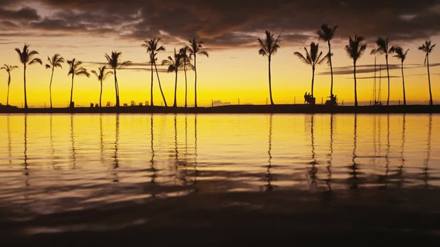 Paradise beach sunset with tropical palm trees. Summer travel holidays vacation getaway colorful concept video from sea ocean water at Big Island, Hawaii, USA