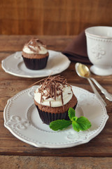 Chocolate cupcakes with cream and chocolate on a wooden backgrou