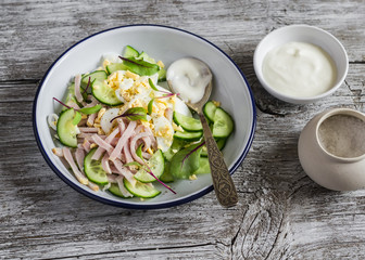 Salad with smoked turkey, cucumber and boiled egg on a light rustic wooden background. Healthy food