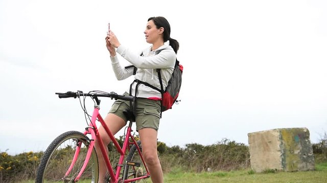 Woman on biking journey taking picture with smartphone