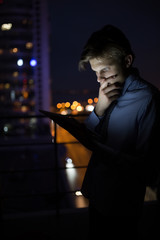 Businessman using his digital tablet late at night