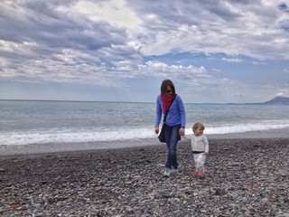 mamma e figlia passeggiano felici sulla spiaggia