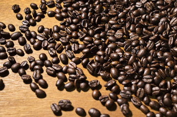 Coffee beans scattered across a wooden table.