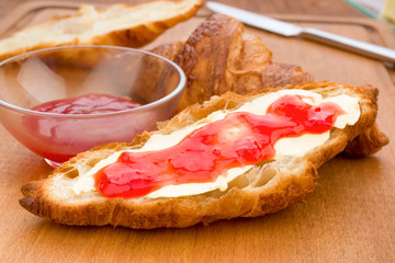 croissant smeared in butter and jam