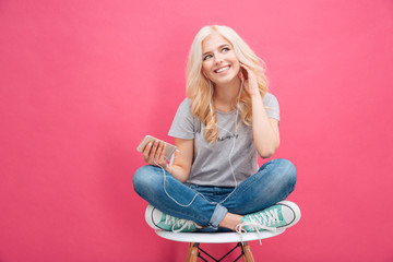 Woman sitting on the chair and listening music in headhpones