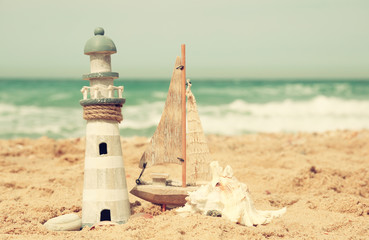 lighthouse, sailboat on sea sand and ocean horizon.