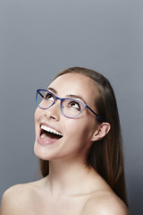 Fototapeta na wymiar Excited young woman in glasses, looking up
