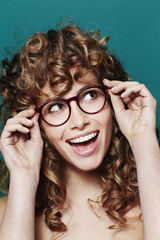 Young woman with curly hair and glasses, looking up