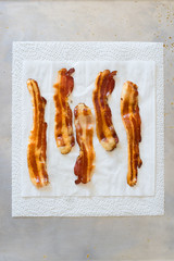 Fried crisp streaky bacon lying on the white paper towel to drain the fat