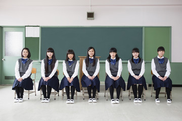 教室で一列に椅子に座る女子生徒 - obrazy, fototapety, plakaty