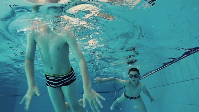 Brothers swimming in the pool, underwater shot