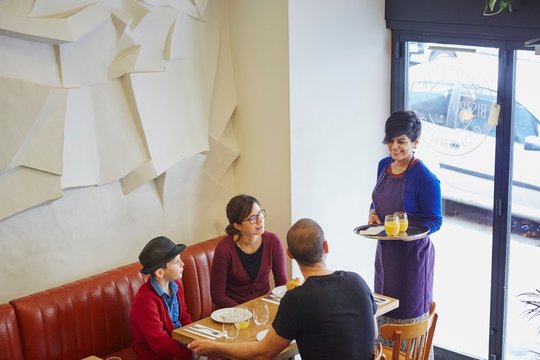 Waitress serving lunch in restaurant to family with son