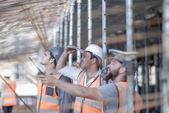 Site manager and builders looking up at steel rod structure on  construction site