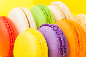 Traditional colorful macarons at yellow background