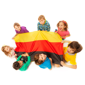 Seven kids holding German flag sitting around it