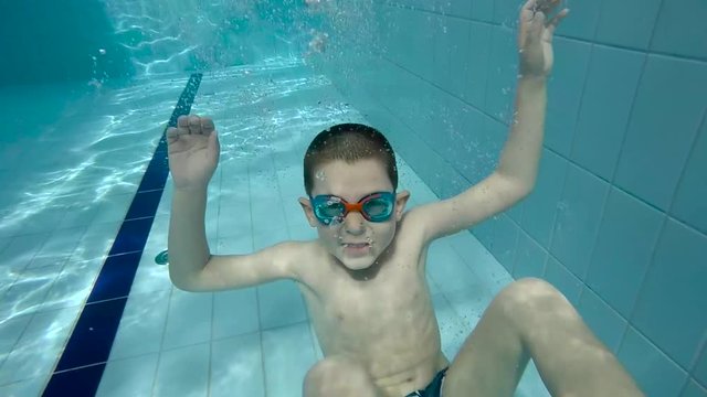 Underwater little kid in swimming pool with goggles.