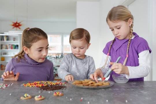 Girls at kitchen counter decorating cookies