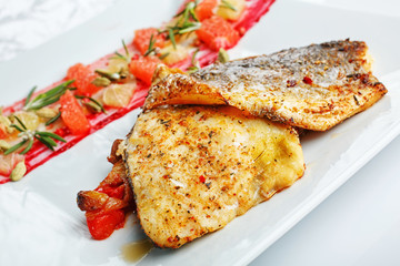 grilled fish with vegetables on a white plate