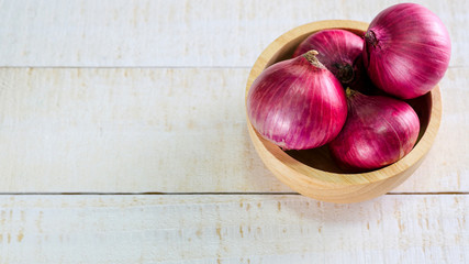 red onions in wooden bowl place on table