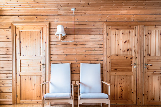 Pinewood interior wall with armchairs and doors in cabin cottage. 