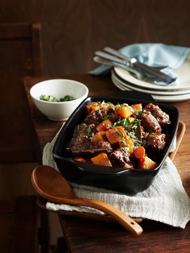 Middle eastern oxtail stew in serving dish with wooden serving spoon