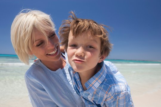 Portrait of boy pulling a face and mother on beach, Majorca, Spain