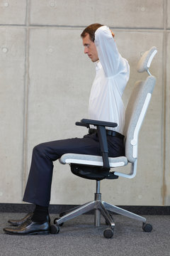 neck tension reduction,stretching with chair in office - business man exercising 