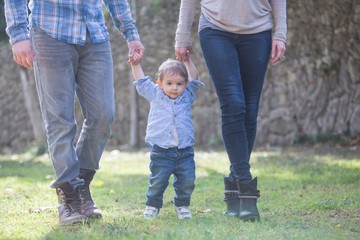 Low section of parents holding baby boys hands