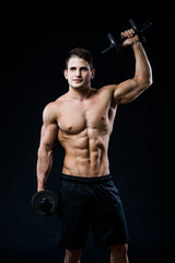 Fototapeta na wymiar Perfect fit athletic guy posing with barbell plate in gym, perfect lat muscle, shoulders, biceps, triceps and chest. Fitness muscular body isolated on dark background.