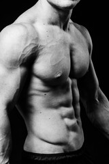 Fototapeta na wymiar Muscular sexy torso of young sporty man with perfect abs close up. Black and white isolated on black background