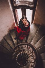 Fototapeta na wymiar Beauty and shape. Young beautiful woman standing on old round wooden staircase.