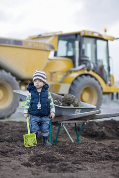 Boy with shovel, digger on background