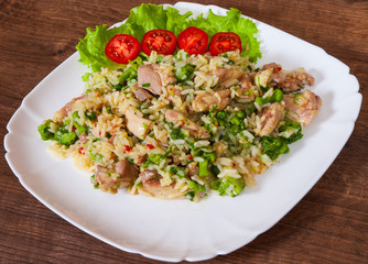 chicken meat with rice and vegetables in a plate on wooden table